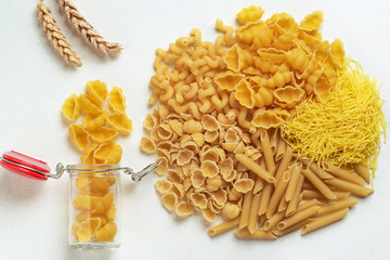 Raw pasta of different types; durum wheat varieties slightly different in a glass jar for storage; top view