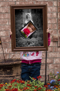 Little girl in the garden with pictures and flowers