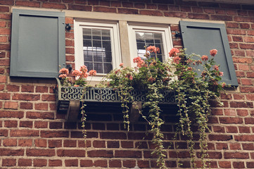 window in a brick wall with pink flowers on a windowsill