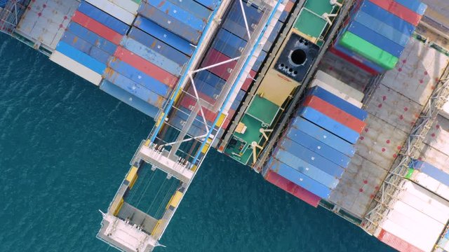 Aerial top view of cargo ship with cargo containers stands on a berth in the port at the loading / unloading of goods