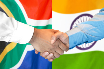 Handshake on South Africa and India flag background.