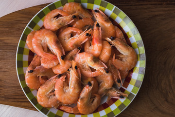 boiled shrimp lie on a plate. these shrimp are unpeeled.