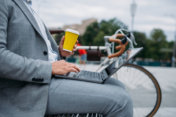 Businessman with cycle drinks coffee on the bench