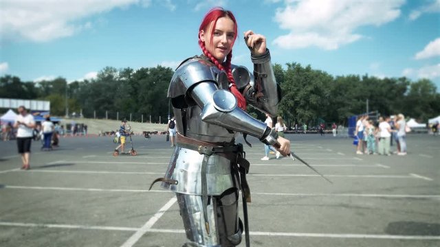 A beautiful red haired girl in a cuirass and full armor training with sword. A sword fight with a shadow 4k