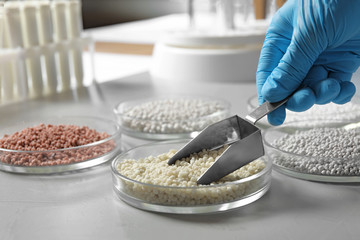 Scientist taking mineral fertilizer with scoop at table, closeup. Laboratory analysis