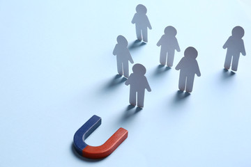 Magnet attracting paper people on light blue background, space for text. Business rivalry concept