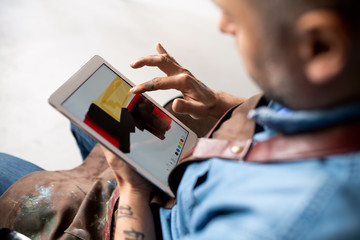 Professional artist in workwear using new program for painting in touchpad
