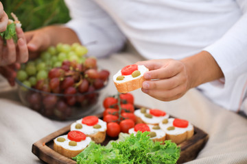Young man with tasty sandwich and woman having picnic at park, closeup
