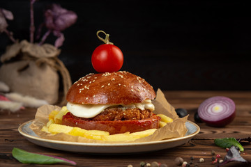 cheeseburger decorated with cherry tomato on a plate on a wooden table