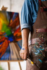 Obraz premium Mid-section of young creative professional painter with paintbrush in hand