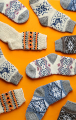 Different knitted socks on orange background, flat lay. Winter clothes