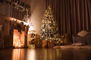 Stylish interior with beautiful Christmas tree and artificial fireplace at night