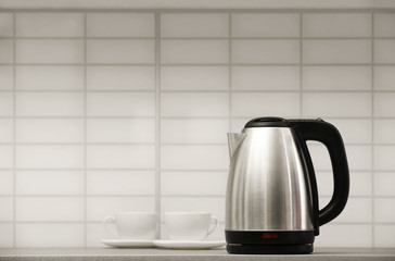 Modern electric kettle and cups on grey kitchen counter. Space for text