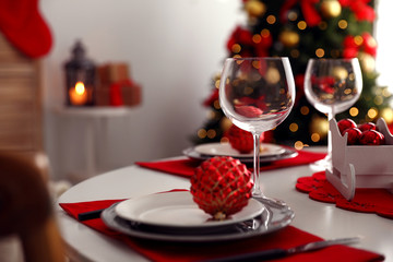 Festive table setting and Christmas tree in stylish room interior
