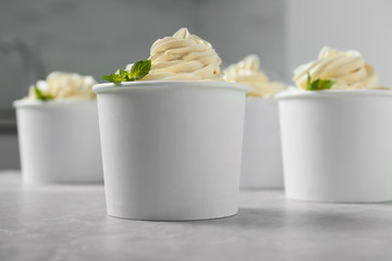 Cups with tasty frozen yogurt on grey table indoors