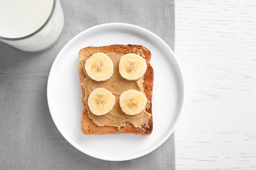 Toast with peanut butter and banana on white wooden table, flat lay. Healthy breakfast
