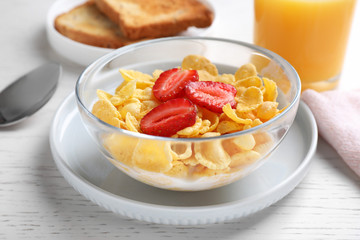 Tasty cornflakes with milk and strawberries on white wooden table, closeup. Healthy breakfast