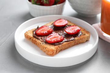 Toast with chocolate spread and strawberries on light grey table, closeup. Healthy breakfast