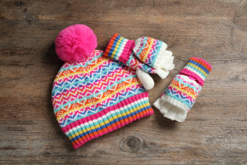 Fototapeta na wymiar Warm knitted hat and mittens on wooden background, flat lay