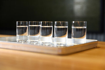 Shots of vodka on bar counter against dark background