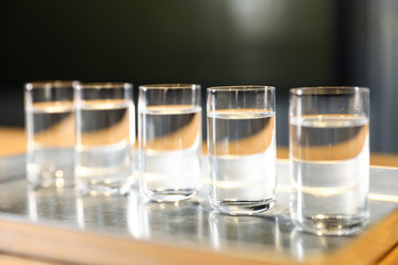 Shots of vodka on bar counter against dark background, closeup