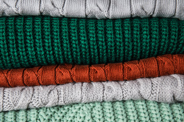 Heap of warm knitted clothes as background, closeup. Cozy autumn