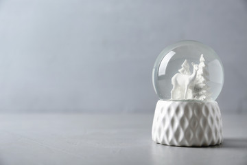 Snow globe with deer and trees on grey table, space for text. Christmas season
