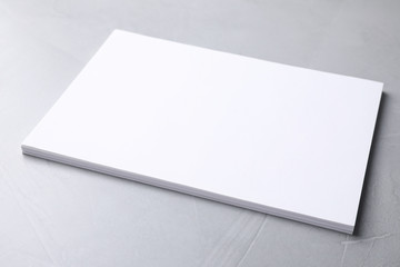 Blank paper sheets on light grey stone background. Mock up for design