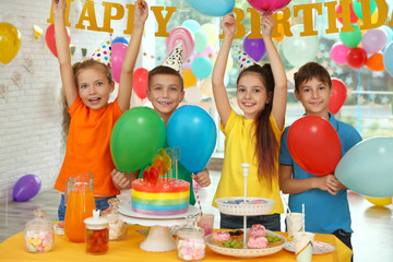 Happy children at birthday party in decorated room