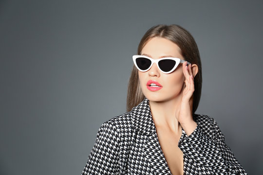 Young woman wearing stylish sunglasses on grey background. Space for text