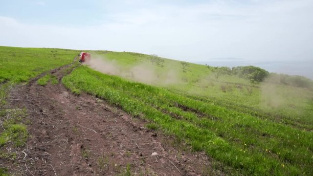 Summer, 2019 - Primorsky Krai, Russia - Orange expedition minibus Sable driving along a dusty dirt road among green fields.
