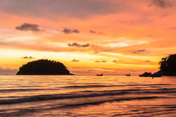 stunning sunset in channel between islands. Koh Pu or crab island is in  the middle between Kata beach and Karon beach.tourists playing blow plat in sunset at Kata beach