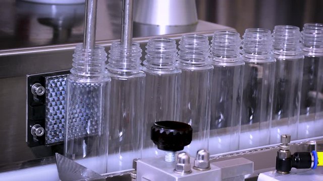 Automated machine on conveyer filling bottles of e-liquid