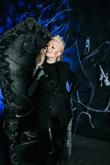 Photo of a female witch queen holding bird and sitting on a gothic scary black throne