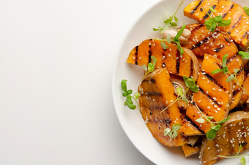 Close up of roasted pumpkin slices on white plate background. Healthy vegetarian, vegan food.