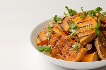 Close up of roasted pumpkin slices on white plate background. Healthy vegetarian, vegan food.
