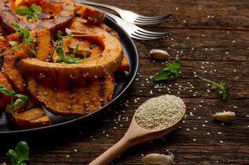 roasted pumpkin slices on old wooden background. Healthy vegetarian, vegan food.
