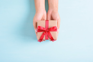 Hands holding gift box with red ribbon for giving
