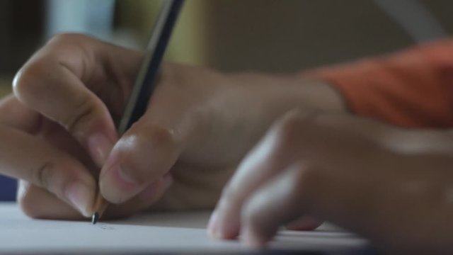 Close up of girl's hand writing with pencil on paper, doing exam test or learning concept with selective focus
