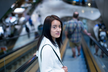 Woman stood on the escalator inside the mall.