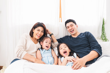 Happy Asian family laying on bed in bedroom with happy and smile
