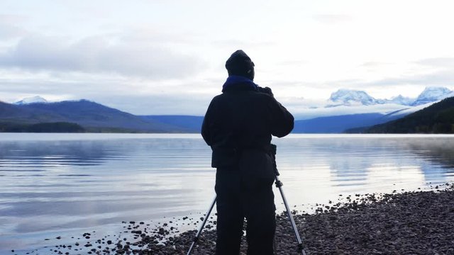 Photographer taking pictures of Lake Mcdonald in Glacier National Park, incredible nature shoots, sunrise and mountains in a fog