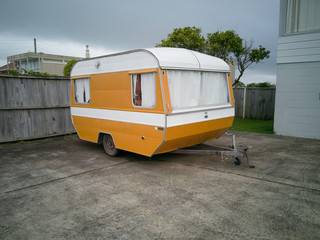 View of old yellow and white camper caravan parked in front of house