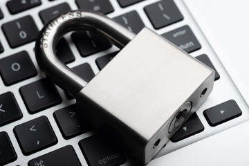 Stainless steel padlock on laptop keyboard, computer protection concept.