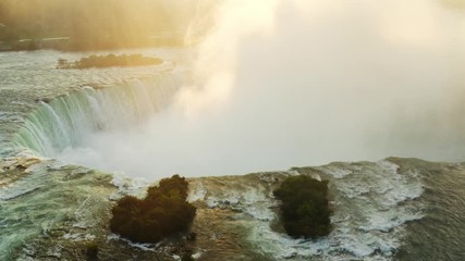Aerial view of Niagara Falls, rocky edge of waterfall,  sunset at famous destination of North America, nature of Northeast USA, fast water flow, dense fog