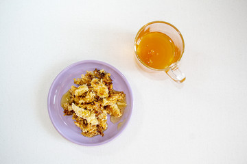 A glass of honey and honeycomb in a saucer