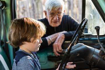 senior grandfather and his 6 year old grandson in vintage pick up truck