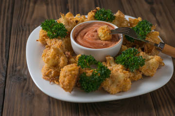 Baked cauliflower in a white bowl with ketchup and mayonnaise sauce.