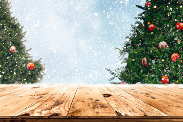 Top of empty wood table with beautiful Christmas tree and snowfall  backdrop. ready for your...