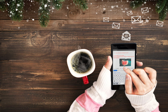 Hand of female using mobile phone to sending E-mail message with email symbol and envelope icon. Christmas and New Year holiday greetings email concept.